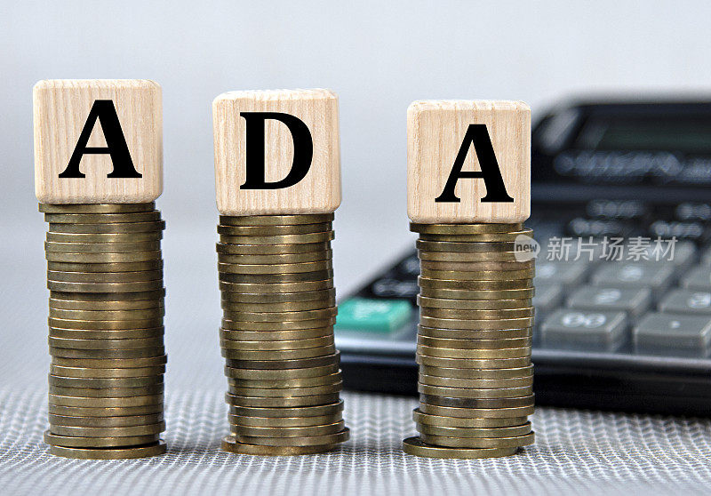 ADA -在硬币和计算器背景上的木制立方体的首字母缩略词